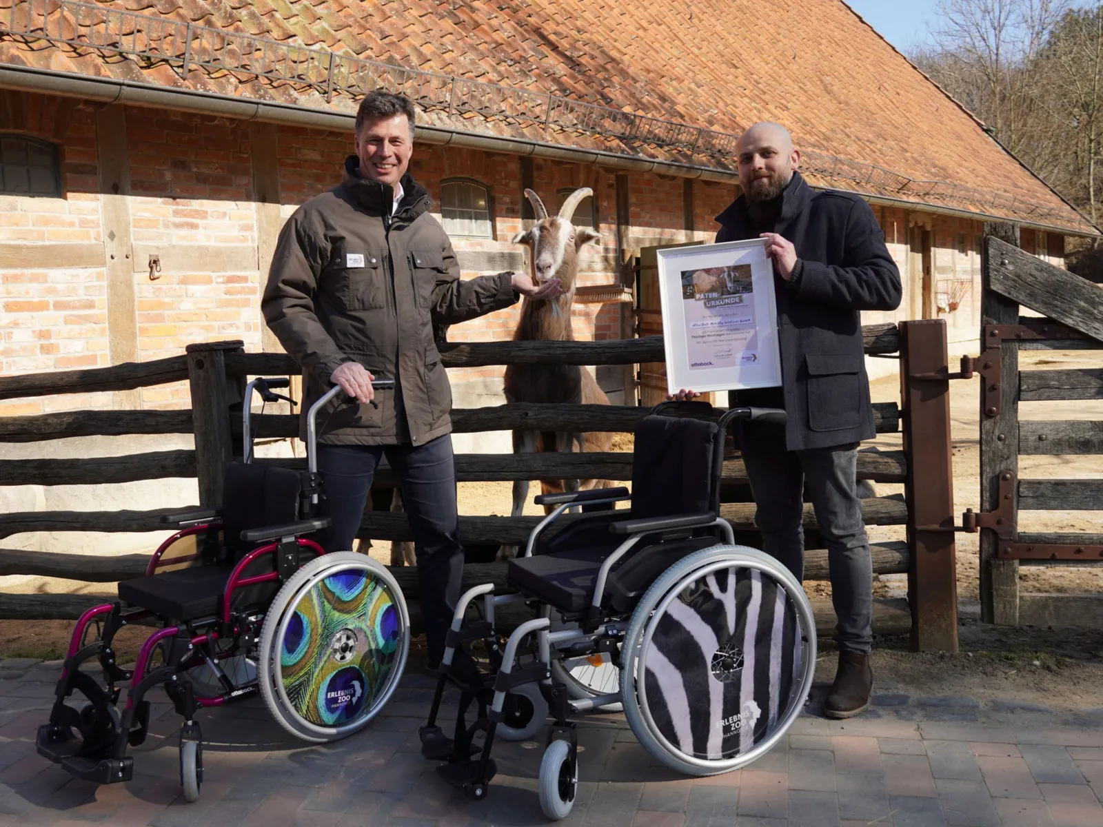Two men are standing next to a wheelchair that people with limited mobility can borrow at the Erlebnis-Zoo.