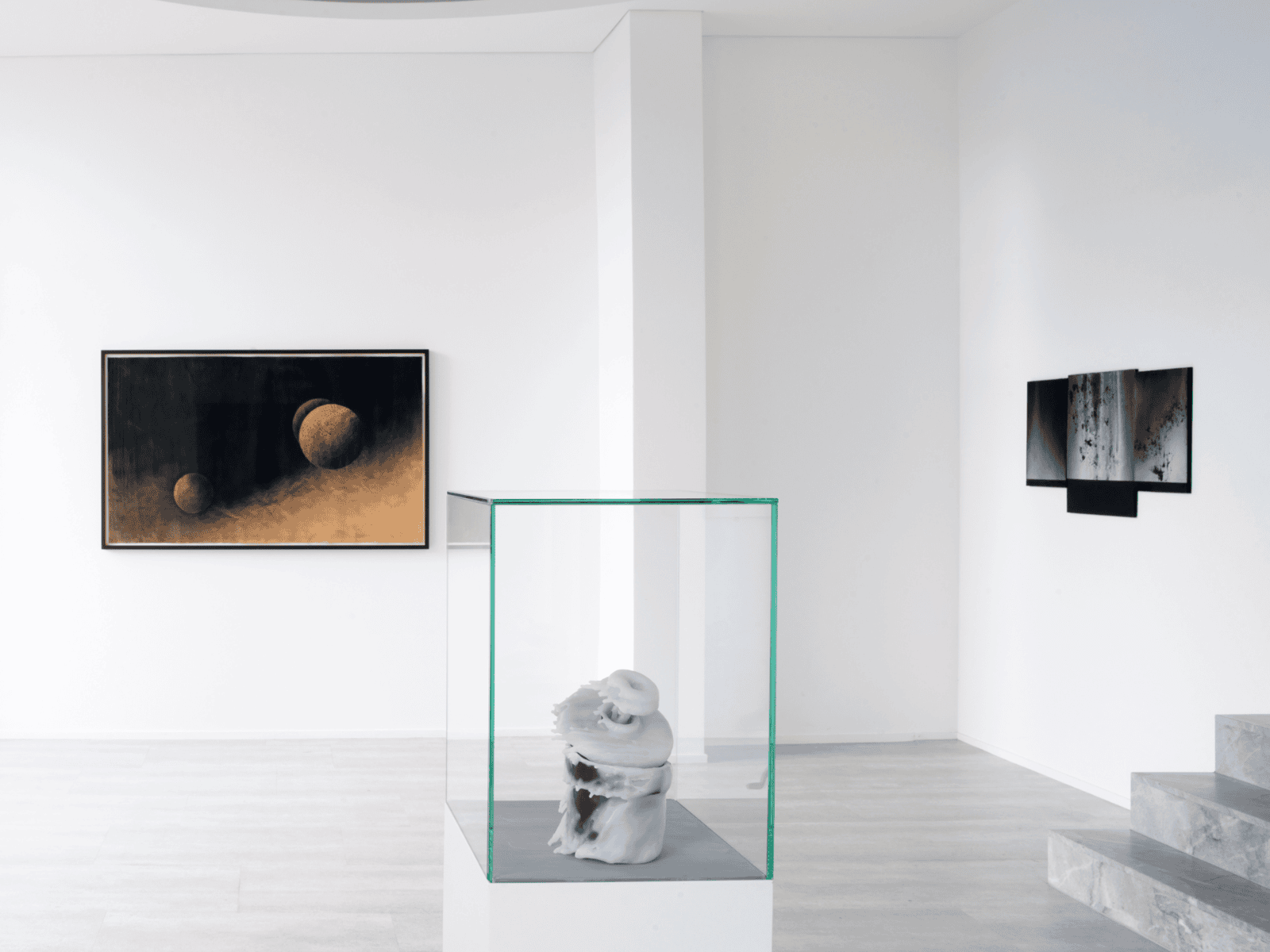 Moderne Galerie mit Skulptur in Glaskasten und zwei abstrakten Wandbildern auf weißem Hintergrund.