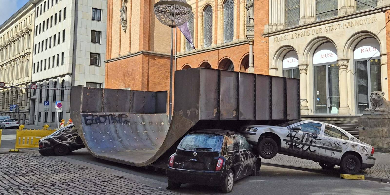 Eine Skater-Halfpipe steht auf einer Stra&szlig;e, davor sind zwei Autos zu einem Unfallgeschehen arrangiert.
