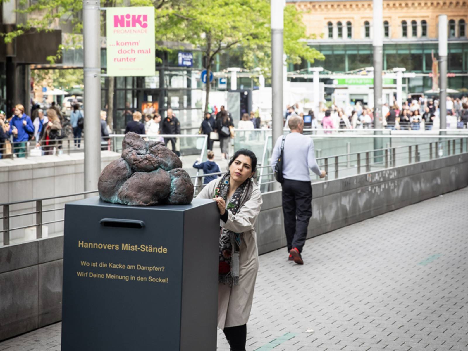 Eine Frau schiebt einen gro&szlig;en Beschwerdebriefkasten durch Hannover
