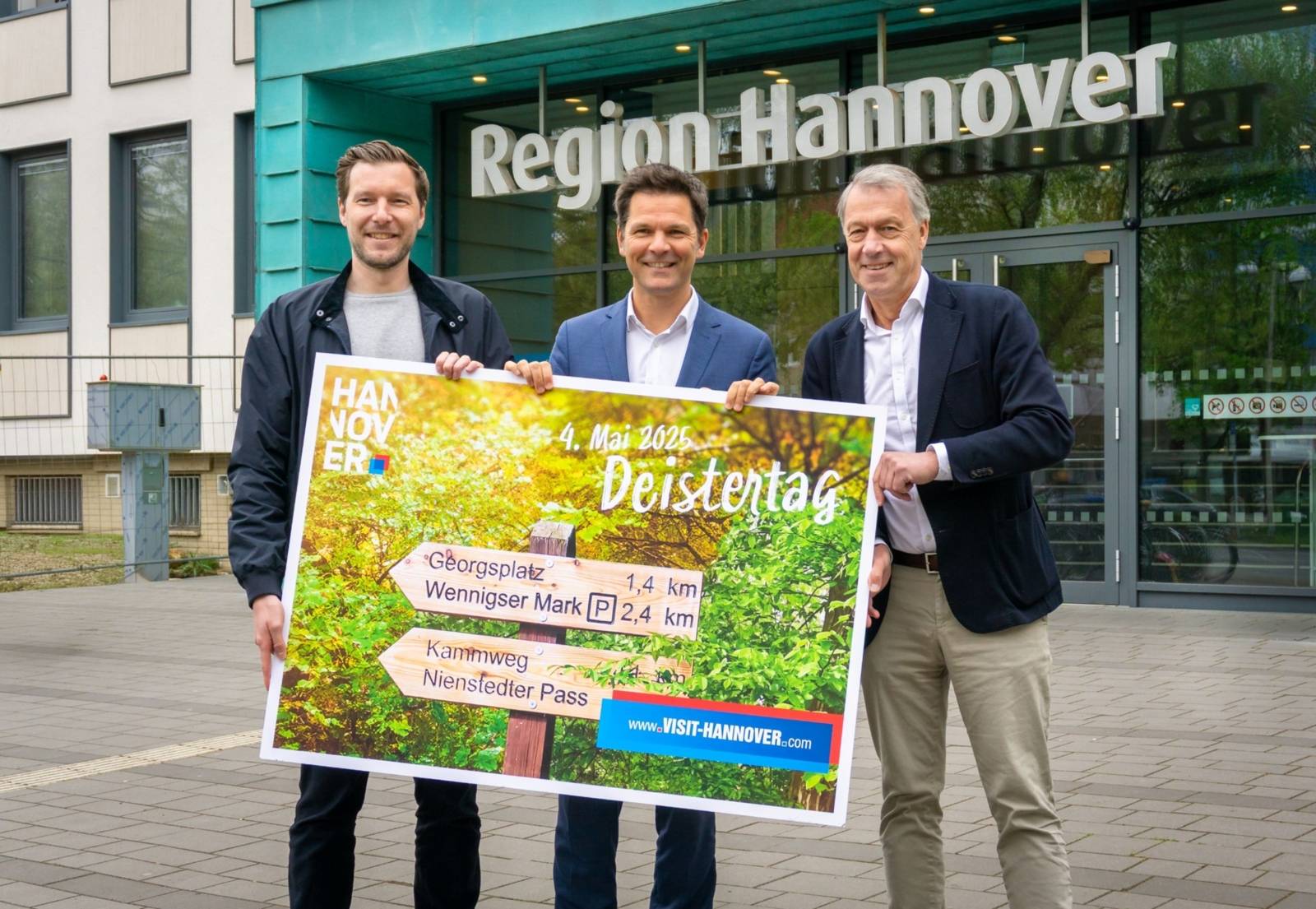 Drei Männer halten ein Plakat zum Deistertag 2025 vor dem Eingang der Region Hannover