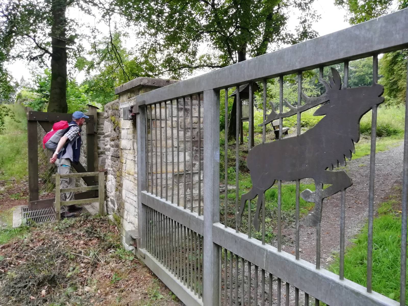 Eine Mauer mit Toren in einem Wald. Ein Mensch geht gerade durch das Tor.