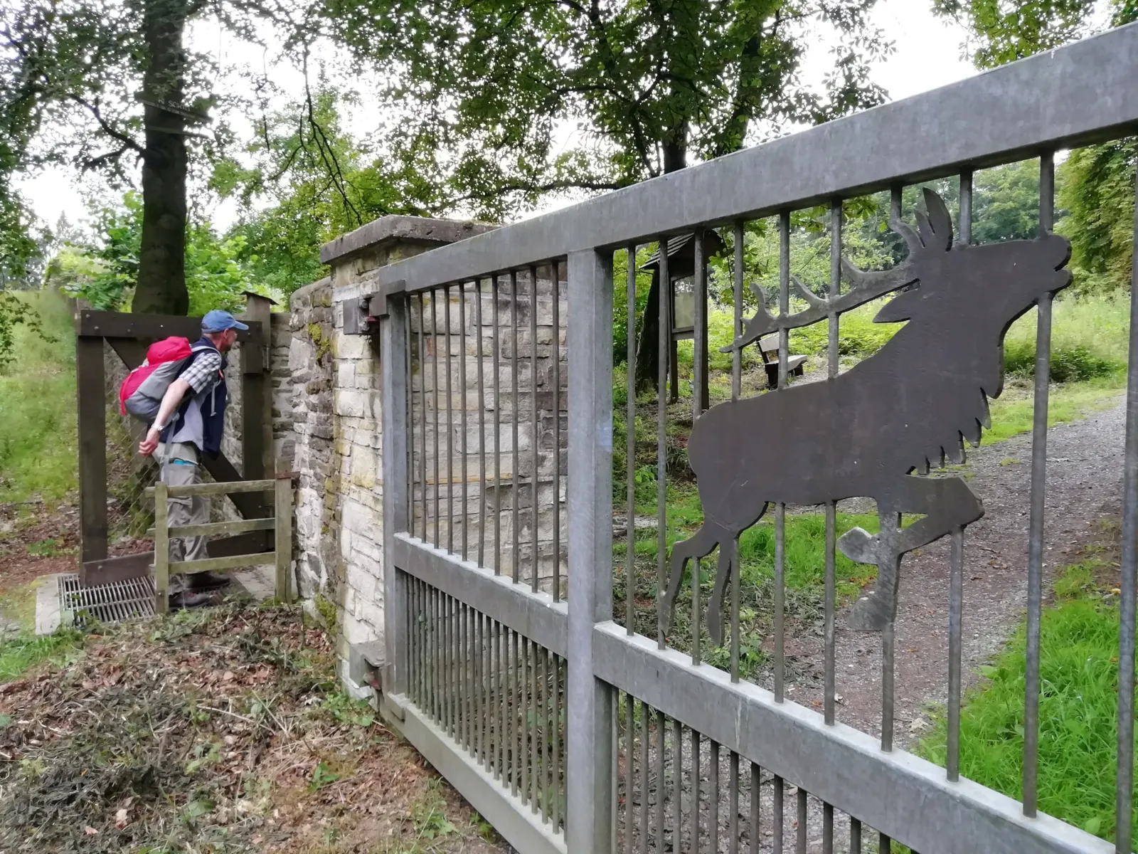 Eine Mauer mit Toren in einem Wald. Ein Mensch geht gerade durch das Tor.