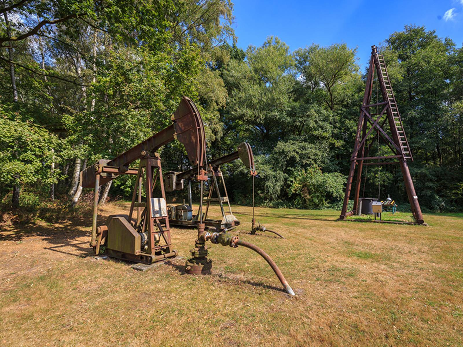  Alte Maschinen zum Abschöpfen des Teers stehen auf einer Wiese.