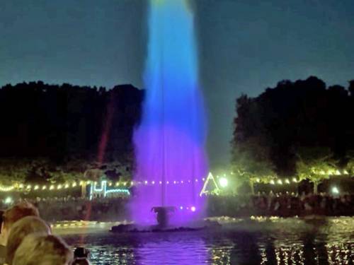 Fântână iluminată în culori variate într-o grădină barocă