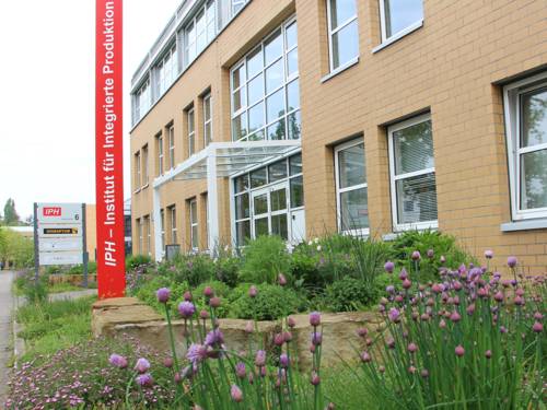 Entrada de un edificio con una columna en la que se lee «IPH – Instituto de Producción Integrada»