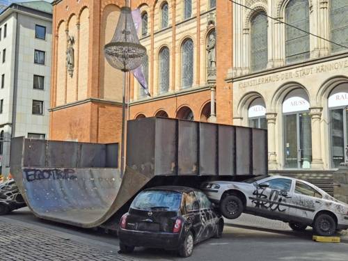 Eine Skater-Halfpipe steht auf einer Straße, davor sind zwei Autos zu einem Unfallgeschehen arrangiert.