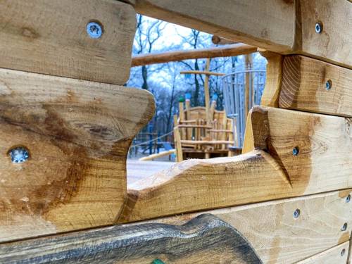 Blick durch ein Schiff im Loch auf einen Spielplatz.