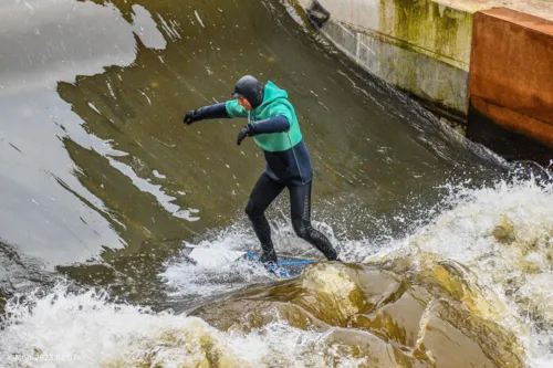 Un uomo in muta da neoprene fa surf sull’onda del Leine.