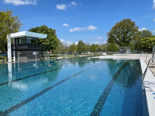 Eingezäuntes, mit Wasser gefülltes, menschenleeres Schwimmbecken, bei Sonnenschein