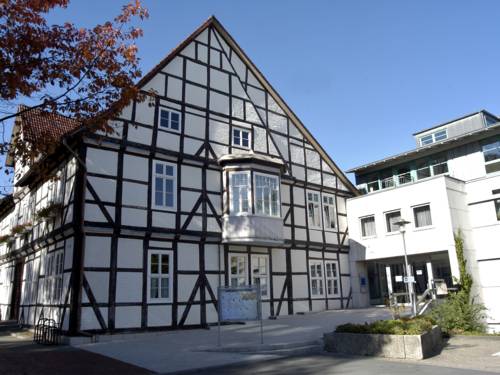Fachwerkhaus mit wei&szlig;en Fenstern und einem wei&szlig;en Erker im ersten OG. Rechts am Fachwerkhaus befindet sich ein moderner Anbau in Kubusform.
