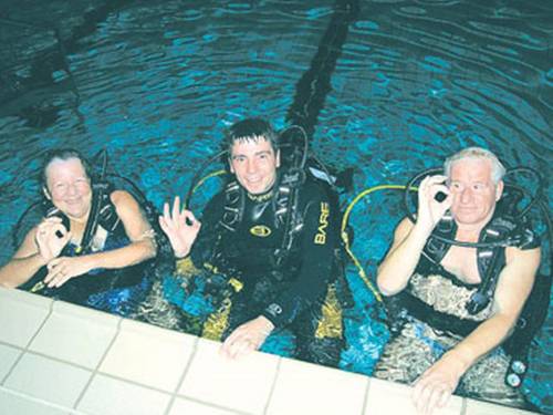 Drei Taucher im Hallenbad, die das OKAY-Zeichen geben