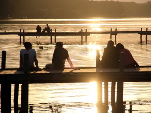 Zwei Steege ragen ins Steinhuder Meer, darauf sitzen sechs Menschen w&auml;hrend die Sonne untergeht.