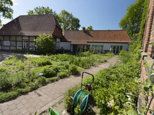 Fachwerkgebäude mit modernem Anbau, davor Beete mit Grünpflanzen
