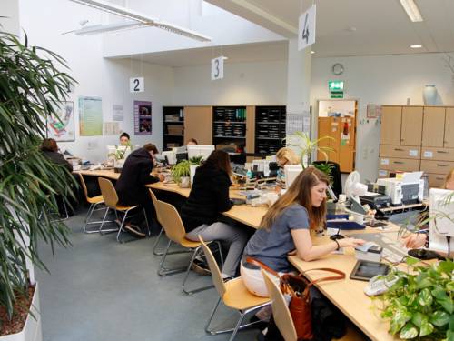Les citoyens et les fonctionnaires dans une grande pièce avec des bureaux et des plantes vertes.