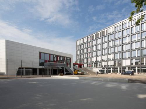 Ein siebengeschössiger Bau, an den sich ein breiter Treppenaufgang anschließt, daneben ein dreigeschössiger Neubau mit Außentreppe.