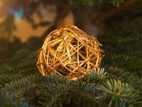 Eine aus Binsen gefertigte Weihnachtskugel an einem Weihnachtsbaum