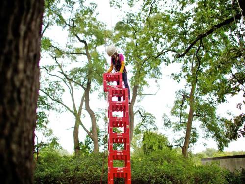 Ein Person stapelt, gesichert durch ein Seil, Getränkekisten aufeinander