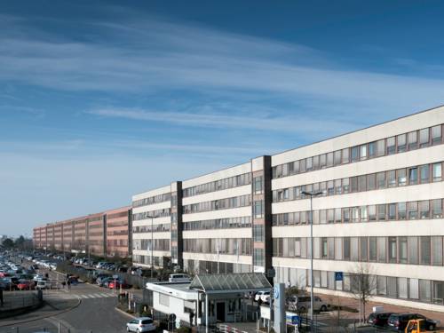 Großes Gebäude mit großer Zahl parkender Fahrzeuge.