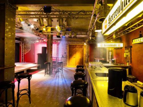 Leerer Musikclub mit Tresen und Barhockern davor.