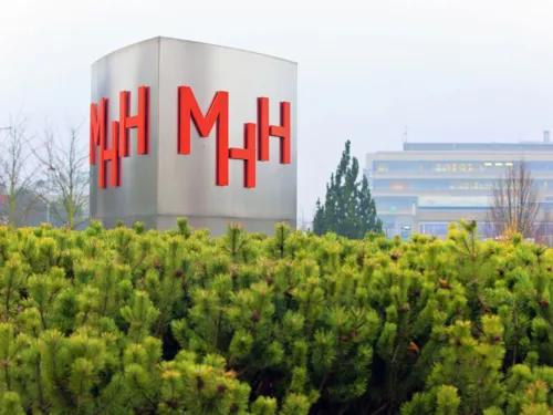 Столб с буквами "MHH", здания на заднем плане.