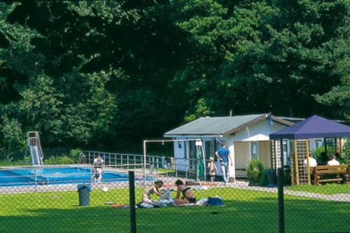 Sunbathing lawn with two bathers, in the background a swimming pool with slide, on the right a building and a blue garden pavilion