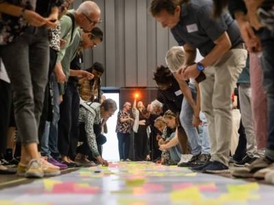 Muitas pessoas debruçam-se sobre post-its coloridos espalhados pelo chão.