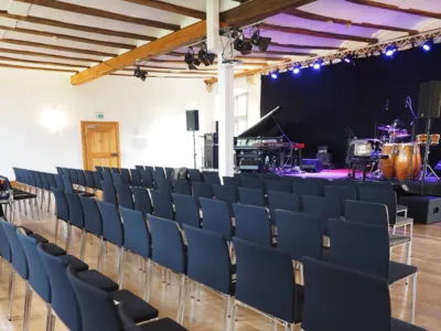 En stor sal i ett slott som används som evenemangslokal. Till höger finns en upphöjd scen med musikinstrument. Framför scenen står flera rader med stolar uppställda.