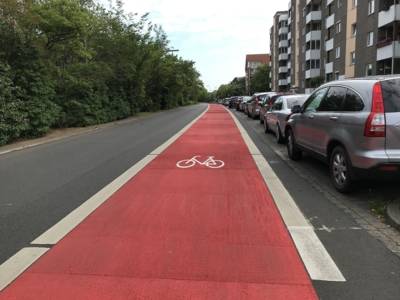 Straße mit roter Markierung und einem weißen Fahrrad-Piktogramm