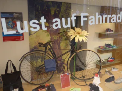 La vitrine d'un magasin, avec des chaussures exposées et un vieux vélo servant de décoration. 
