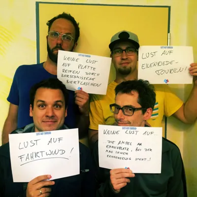 Quatre hommes tenant des pancartes sur lesquelles ils sont eux-mêmes représentés