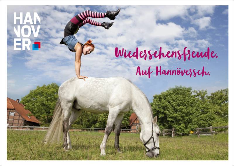 Ein Mädchen macht einen Handstandauf einem Pferd.