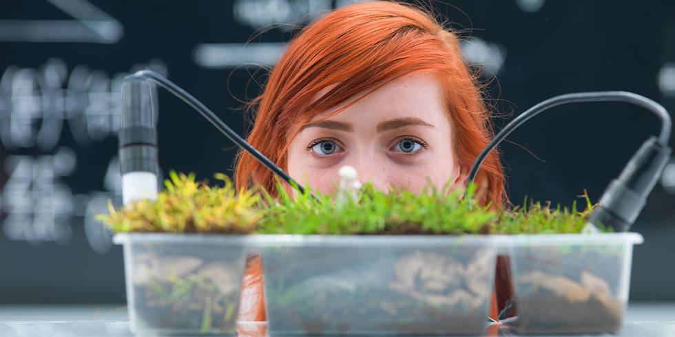 close-up of a student in a chemistry lab curiously observing grass experiment