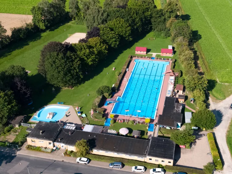 Luftbild vom Freibad mit Schwimmbecken, Kleinkindbecken, Gebäuden und Liegewiese