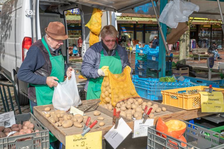 Zwei Menschen f&uuml;llen ihren Kartoffelstand auf.