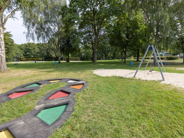 Schaukel und andere Spielgeräte auf einer Rasenfläche