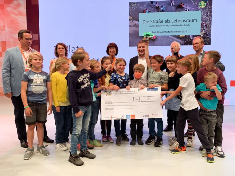 Grundschüler erhalten auf einer Bühne einen Scheck.