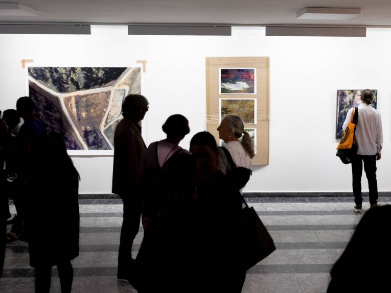 Publikum blickt auf Werke im Regionshaus, Schauplatz für Kunst. Die Bilder zeigen Menschen Topografie.