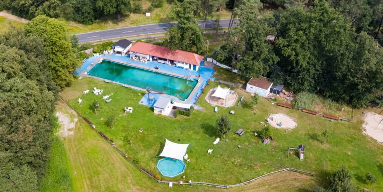 Luftbild eines in einem Waldgebiet gelegenen Freibades