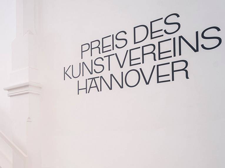 Das Foto zeigt eine weiße Wand in den Räumlichkeiten des Kunstvereins Hannover, auf der der Schriftzug „Preis des Kunstvereins Hannover“ steht.