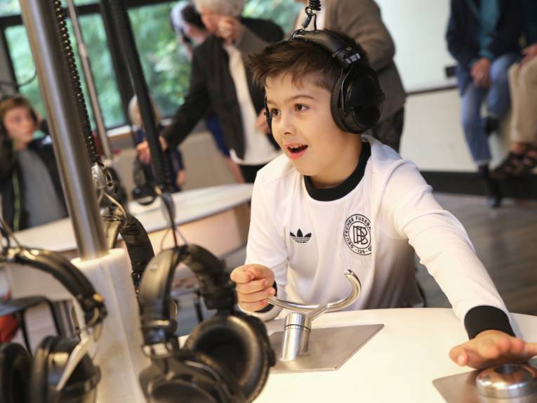 Ein Junge an einem Tisch mit Kopfhörern und Buzzern.