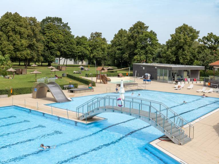 Außenschwimmbecken mit Brücke zwischen Schwimmer- und Nichtschwimmerbereich und Rutsche im Nichtschwimmerbereich