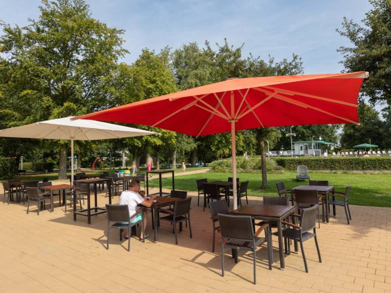 Terrasse moit Tischen, Stühlen und farbigen Sonnenschirmen