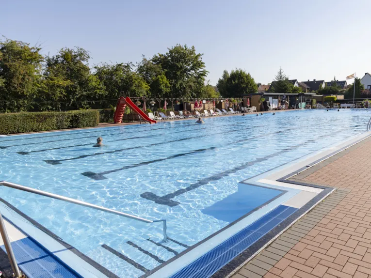 Schwimmbecken mit Badeg&auml;sten und Rutsche
