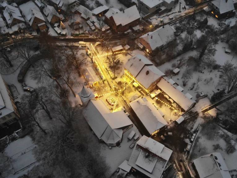 Blick auf einen dörflichen Weihnachtsmarkt von einer Drohne aus der Höhe.