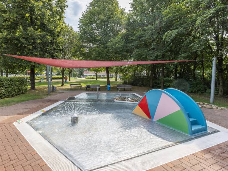 Ein flaches Becken , mit Sprenkleranlage und einer kleinen Rutsche