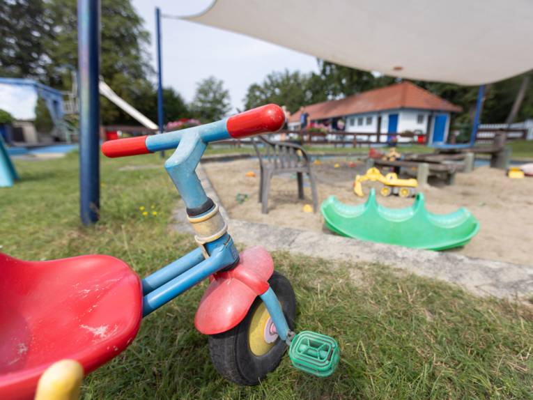 Im Vordergrund Dreirad, Kunststoppwippe, Sandkiste mit Bagger