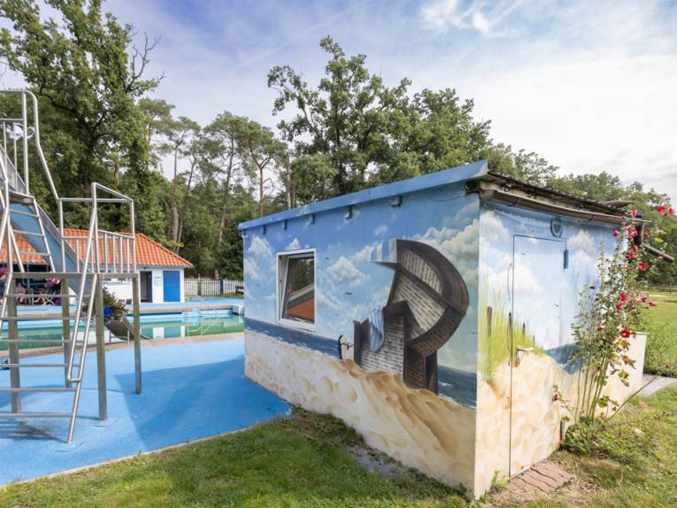 Große Metallrutsche, daneben ein Gebäude auf das eine Strandlandschaft mit Strandkorb gemalt ist