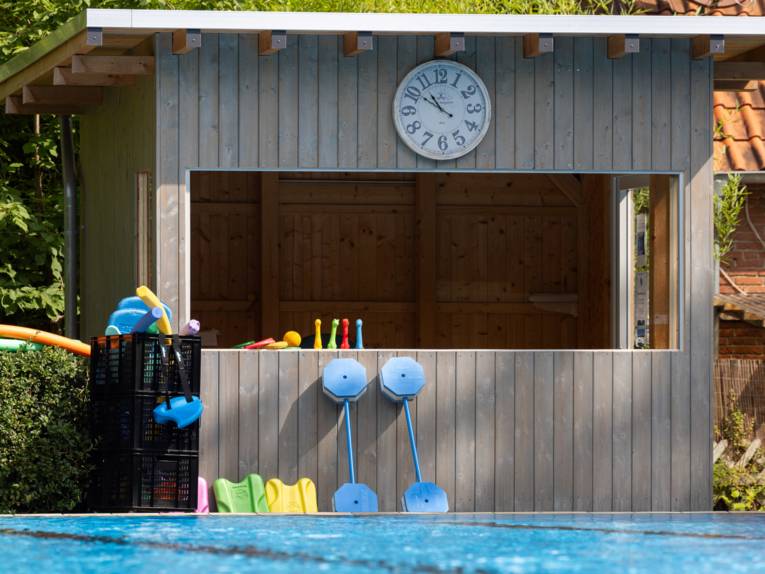 Holzhütte, vor der Schwimmhilfen und Schwimmspielzeug liegt
