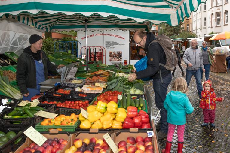 Ein Vater mit seinen Kindern am Gem&uuml;sestand